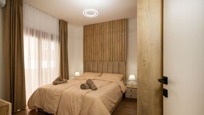 Un dormitorio con una cama, dos mesitas de noche con lámparas, un cabecero de madera y una puerta de madera.