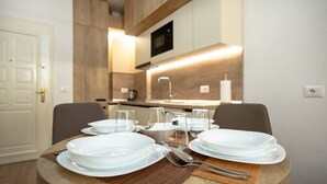 Una mesa de comedor dispuesta con platos, vasos y cubiertos en una cocina moderna con armarios de madera y un microondas.
