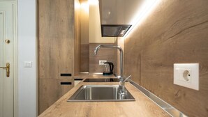 Una cocina moderna con un lavamanos de acero inoxidable, armarios de madera y una campana extractora empotrada.
