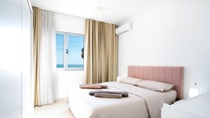 Un dormitorio con cama, ventana, cortinas y aire acondicionado.