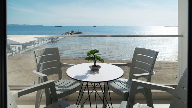 Balcón con una mesa redonda y dos sillas, con vistas a una playa y al mar.
