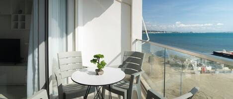 Un balcon avec une table ronde et deux chaises, donnant sur une plage et la mer.