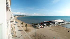 Vista de la playa con cielo despejado, arena dorada y un edificio de techo plano con un letrero.