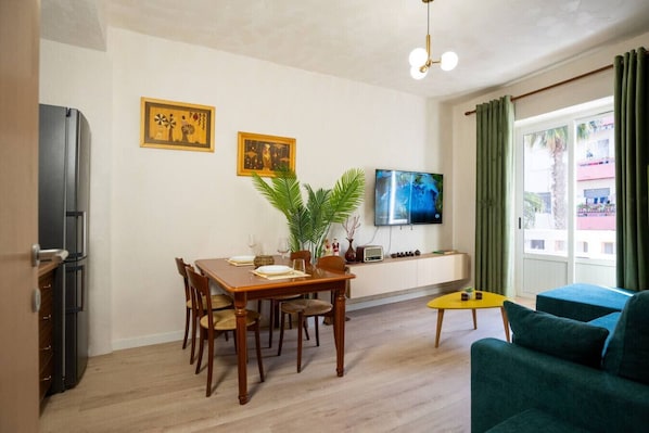 Ein modernes Wohnzimmer mit Essbereich, einem Flachbildfernseher und einem grünen Sofa.