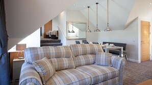 A loft-style living area with a sofa, dining table, and pendant lights. - Loch View Apartment in Fort William Town Centre (Fort William)