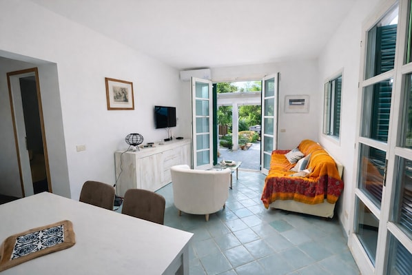 A compact living space with a dining area, a sofa, and a television.