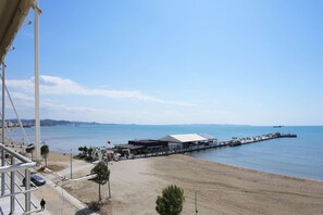 Une vue sur la côte, avec une plage, une jetée qui s’avance dans la mer et un bâtiment doté d’un toit plat.