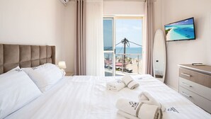 Une chambre d’hôtel avec un grand lit, une télévision, un bureau et une vue sur la plage.