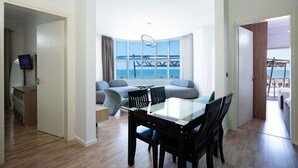 Un salon moderne avec un coin repas, de grandes fenêtres offrant une vue sur la mer et un balcon avec vue sur la mer.