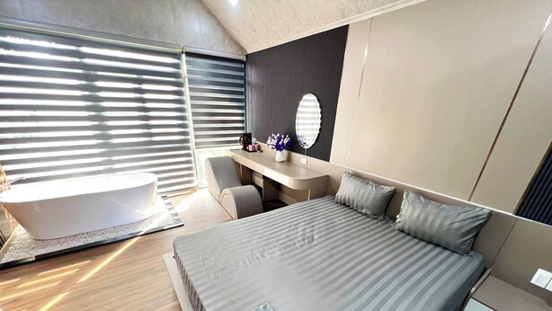 Quarto moderno com uma cama grande, uma escrivaninha e uma banheira.