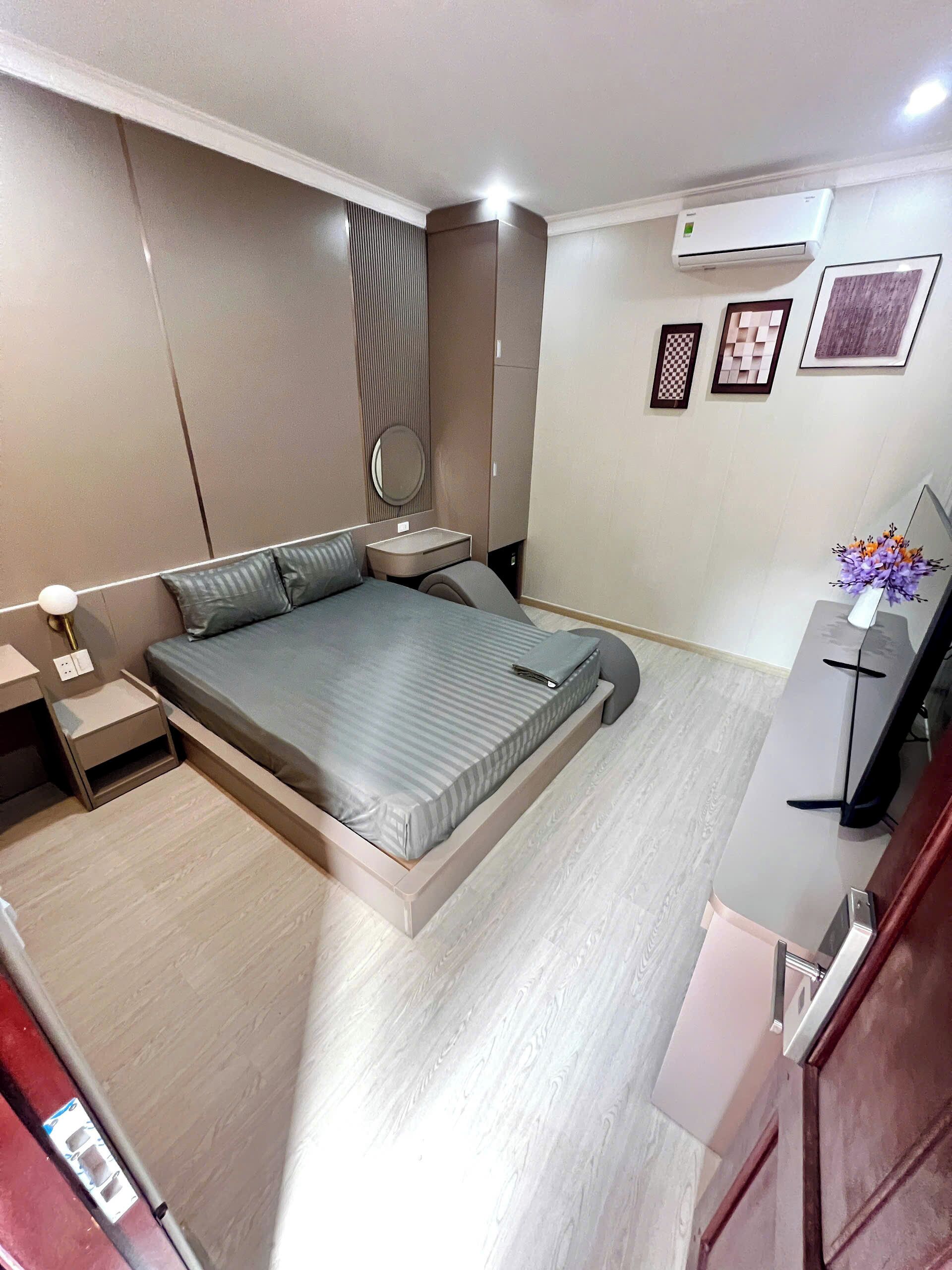 A modern bedroom with a bed, bedside tables, a mirror, and a desk with a chair.