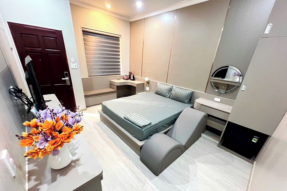 A modern bedroom with a bed, bedside table, and a mirror.