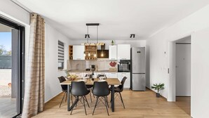 A modern kitchen with a dining area, a refrigerator, and a potted plant. - Apartment EM – Peaceful Stay near Poreč for 4 Guests (Poreč)