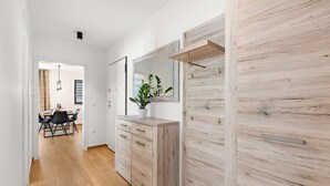 A modern interior with a wooden floor, a dining area with a table and chairs, a cabinet with drawers, and a large mirror on the wall. - Apartment EM – Peaceful Stay near Poreč for 4 Guests (Poreč)