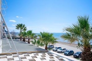 A parking area with cars, palm trees, and a beach view.