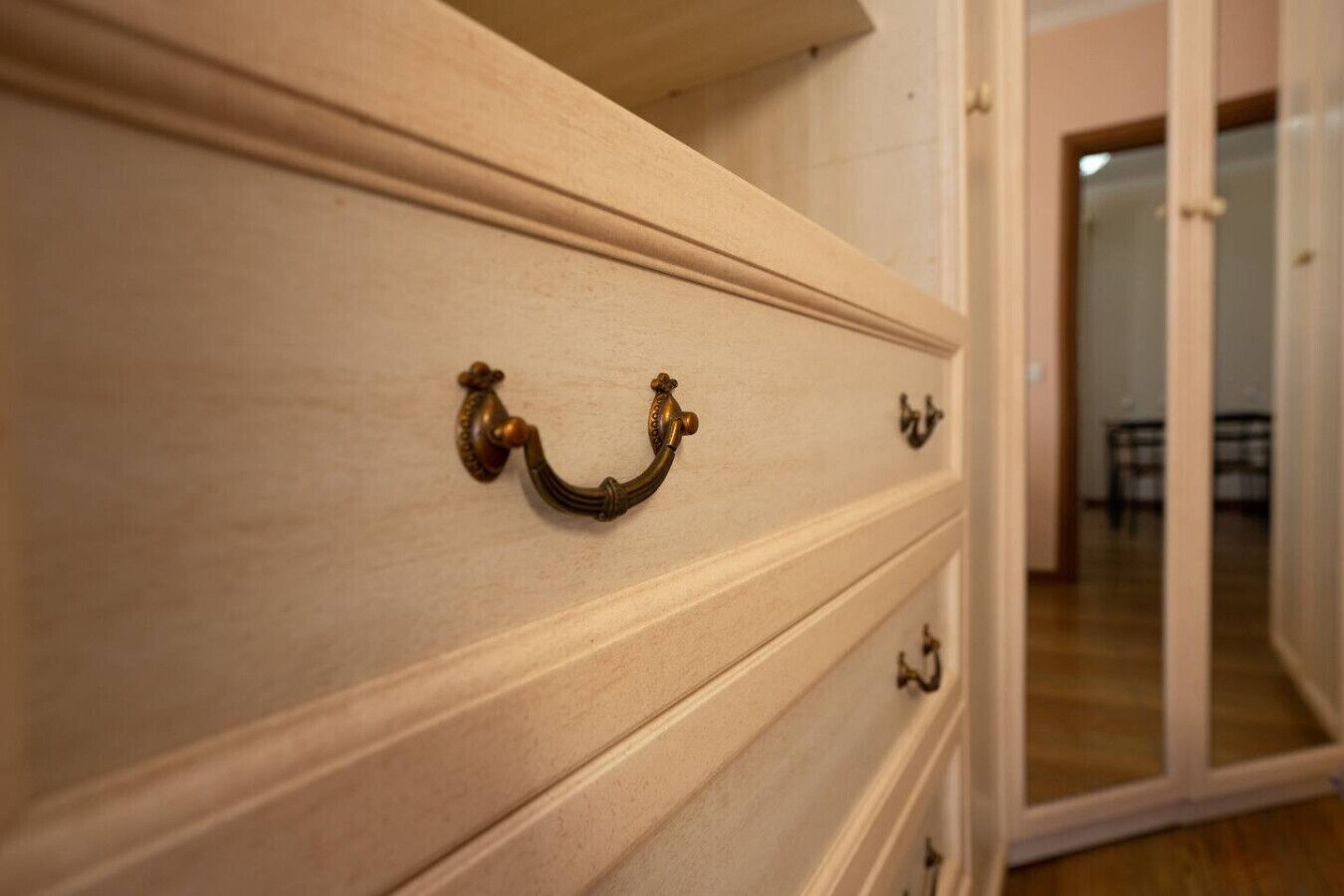 A close-up of a wooden dresser with brass handles.