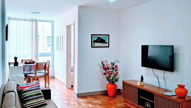 Un soggiorno moderno con un divano, una televisione, un pavimento in legno e un'area pranzo con tavolo e sedie.