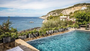 Una piscina con vista al mar y una colina con edificios.