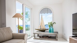 Una sala de estar moderna con un sofá, una mesa con un modelo de velero, una lámpara y un televisor.