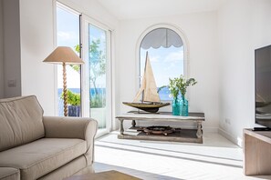 Ein modernes Wohnzimmer mit einer Couch, einem Tisch mit einem Modell eines Segelboots, einer Lampe und einem Fernseher.