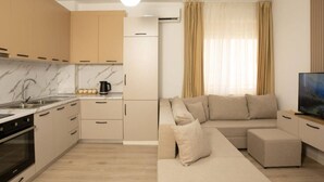 Eine moderne Küche mit Marmorarbeitsplatten, einem eingebauten Ofen und einem Essbereich mit einer Couch und einem Fernseher.