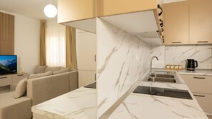 Eine moderne Küche mit Marmorarbeitsplatten, einer integrierten Spüle und einem Essbereich mit einer Couch.