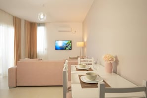 Una habitación de hotel moderna con sofá, mesa de comedor y televisor.