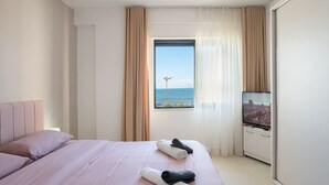 Una habitación de hotel con cama, televisión y ventana con cortinas.