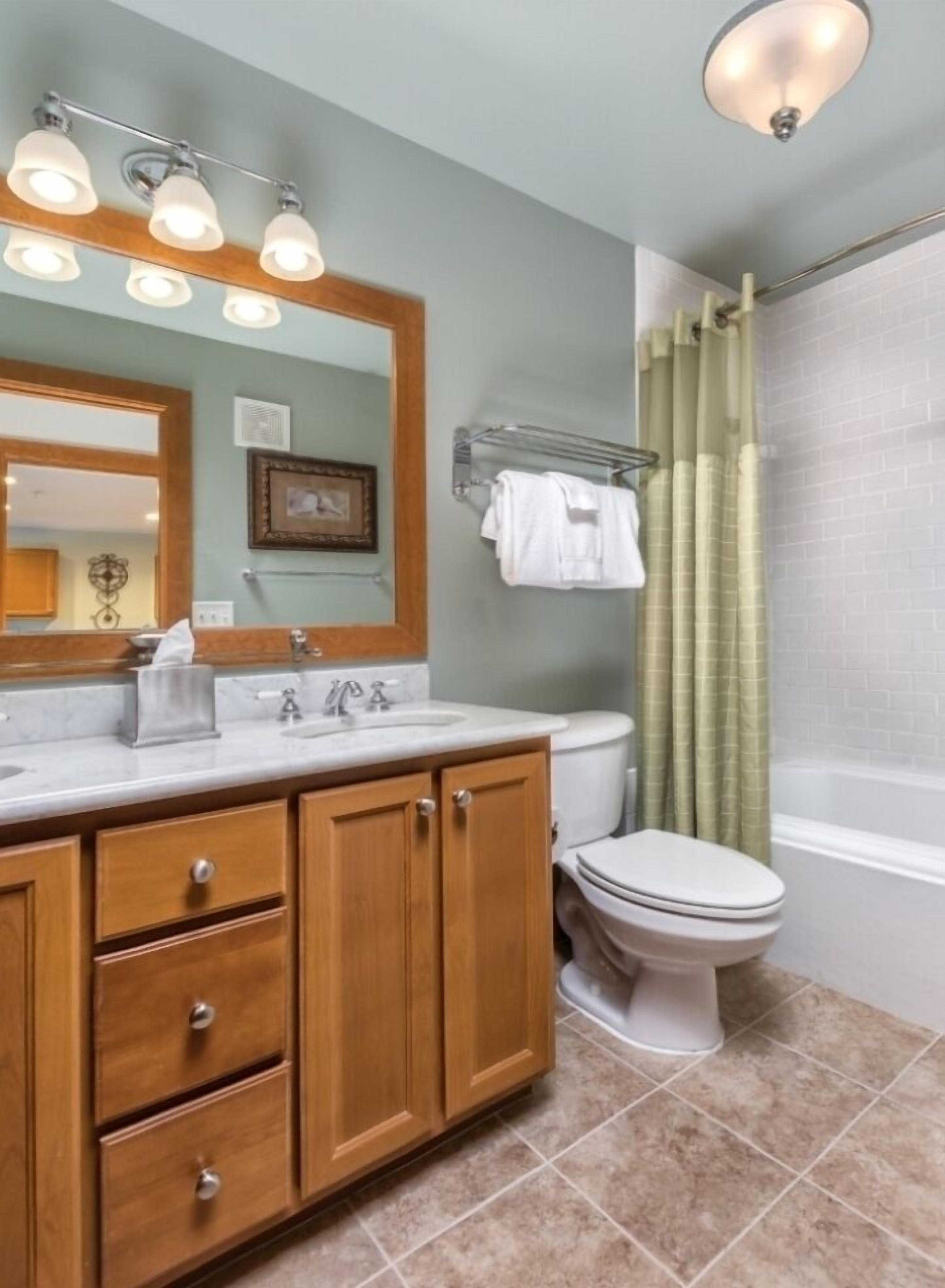 A bathroom with a wooden vanity, a sink, a toilet, and a shower curtain.