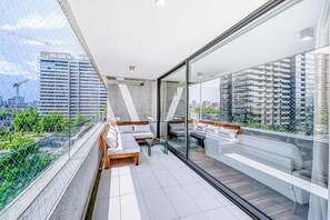 A modern balcony with a glass railing, white sofas, and a small table. - Brisa Capital 2BR - Wifi, Estacionamiento & Shopping Mall (Santiago)