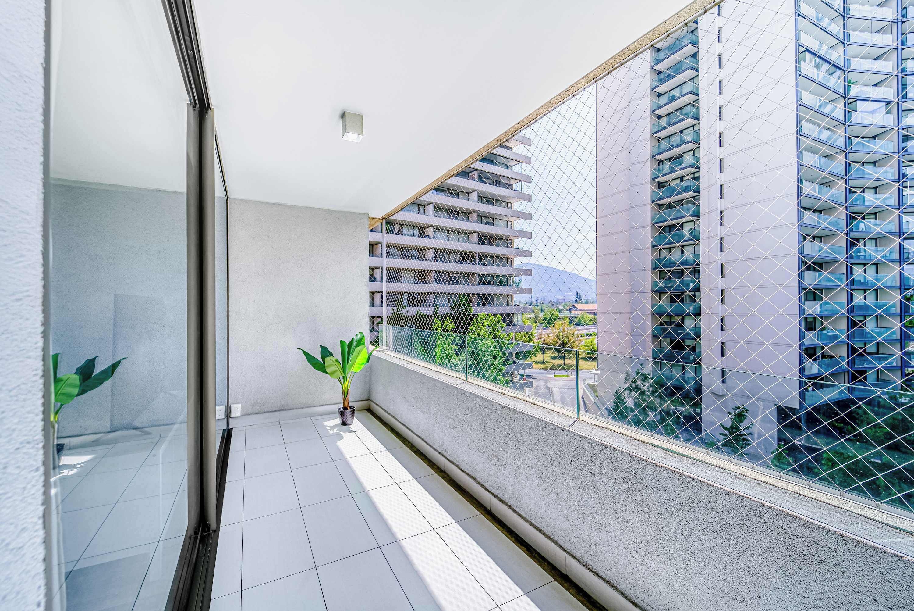 A balcony with a potted plant, a glass door, and a view of a modern building.