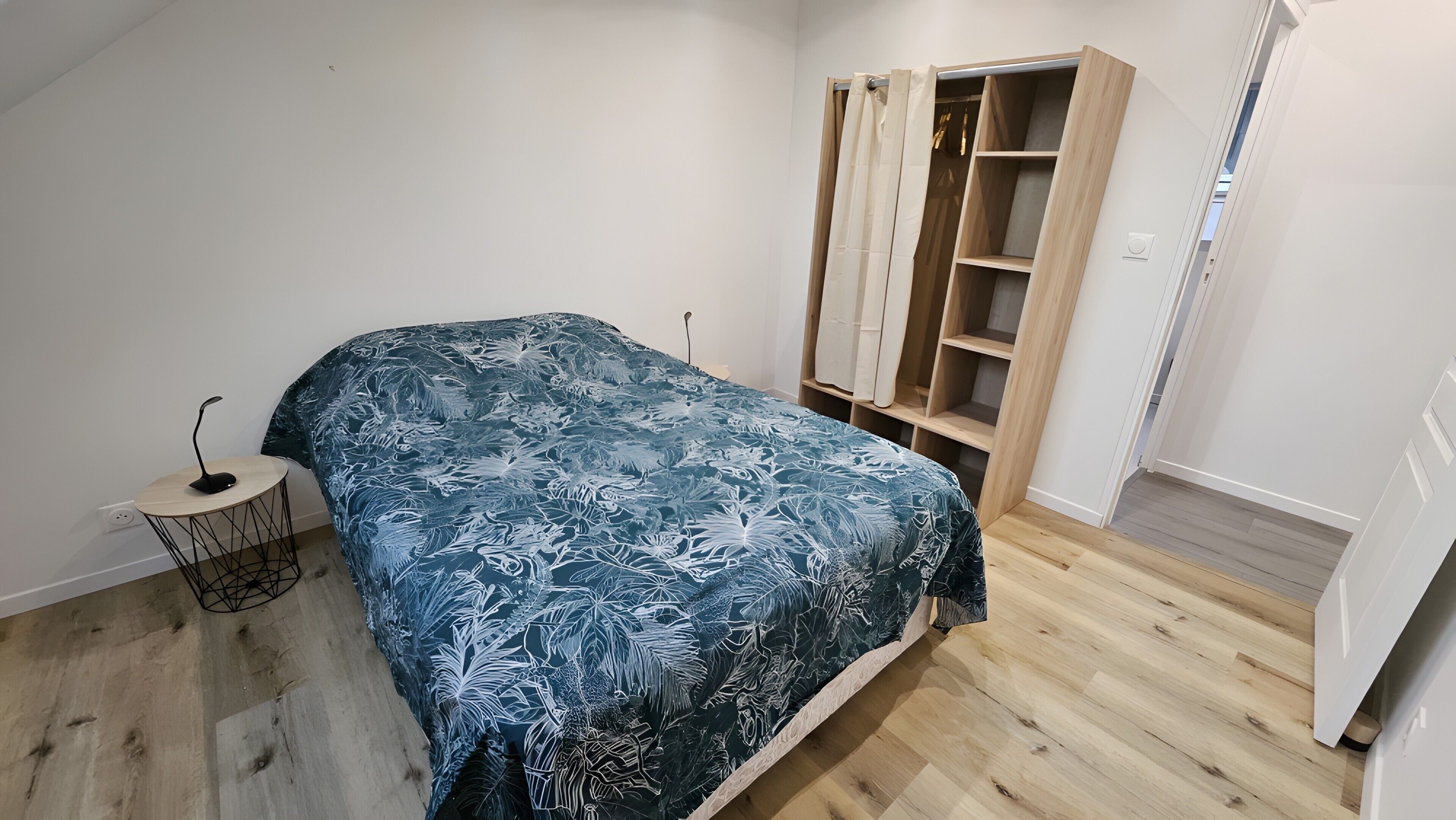 Une chambre à coucher comprenant un lit, une table de chevet, une armoire et un petit tabouret.