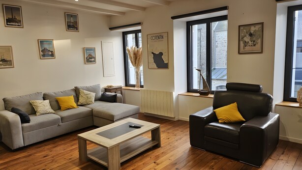 Una sala de estar con un sofá, una mesa de centro, un sillón de cuero y un ventanal con vistas.