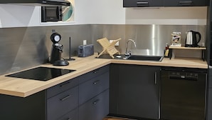 Una cocina moderna con microondas, tostadora, pileta y muebles bajos negros.