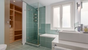 Un baño moderno con ducha de vidrio, un lavamanos blanco y un espejo grande sobre el lavamanos.