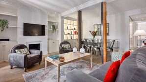 Amplia sala de estar con chimenea, televisor y comedor con sillas y mesa.