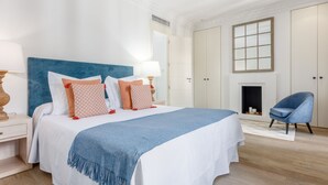 Un dormitorio con una cama grande, una silla azul, una chimenea y un guardarropa.