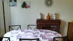 Un coin repas avec une table ronde recouverte d’une nappe à motifs, entourée de chaises noires.