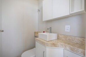 A bathroom with a white sink, a mirror, and a cabinet. - Feel the sea Breeze in This Condominium 220m From the Beach - Ibhs (Barra Velha)