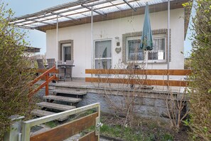 Un immeuble résidentiel doté d’un porche couvert, d’un escalier en bois et offrant une vue sur les environs.