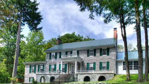A stone building with green shutters, a covered porch, and a chimney. - Stock's Manor Bed and Breakfast #1 (Mechanicsburg)