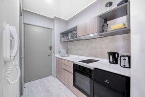 A compact kitchen with a built-in oven, a dishwasher, a coffee maker, and a toaster. - Carmen Studio - Wifi, Estacionamiento, Gym, Metro (Santiago)