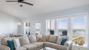A living room with a sectional sofa, a dining area, and large windows with a view. - Ocean Club N303, Soundfront Condo in Indian Beach! (Indian Beach)
