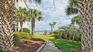 A pathway leading to a grassy area with palm trees and a view of the ocean. - Ocean Club N303, Soundfront Condo in Indian Beach! (Indian Beach)