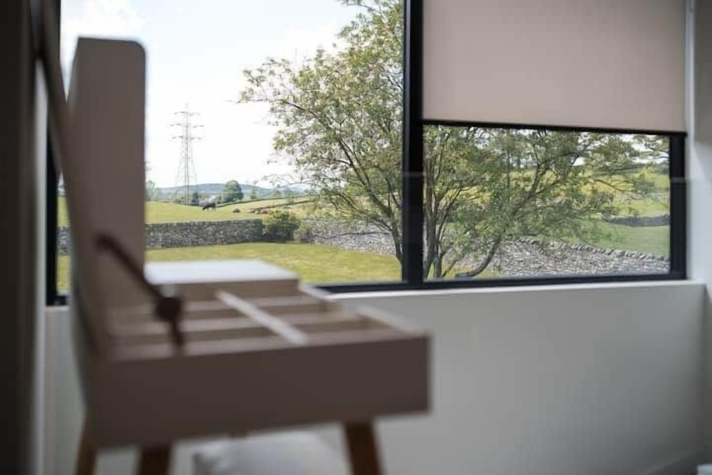 Een kamer met een groot raam, een houten stoel en uitzicht op een landelijk gebied.