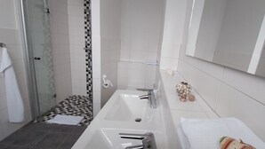 Un bagno con doccia in vetro, un lavandino bianco e uno specchio.