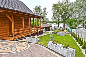 Ein Holzhaus mit Veranda, einem Kiesweg und einem Garten mit Pflanzkästen.