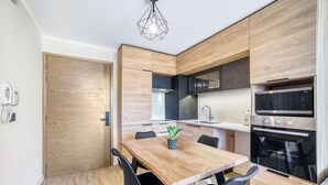 A modern kitchen with wooden cabinetry, a built-in oven, and a dining table with chairs.