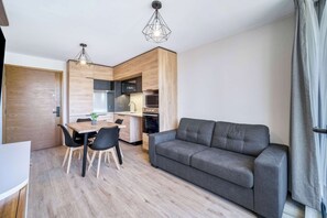 Une cuisine moderne avec des meubles en bois, une table à manger avec des chaises et un canapé gris.