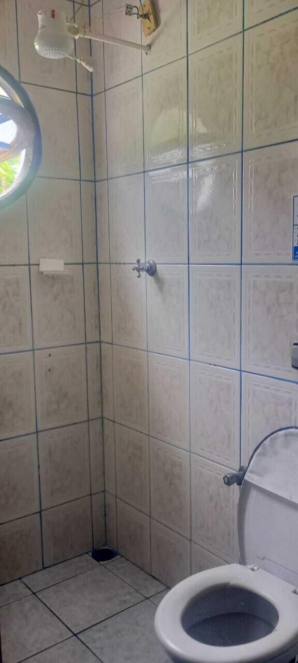 Ein kleines Badezimmer mit Toilette, Duschbereich und einer Lampe.